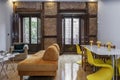 Living room with vintage brick wall with wooden and metal beams, brown wooden shutters and yellow decorative details Royalty Free Stock Photo