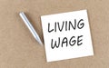 LIVING WAGE text on a sticky note on cork board with pencil