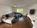 Livingroom with big grey sofa and flatscreen TV white walls