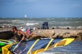 Livorno, Italy - August 2017: Old Woman Sitting on the Rocks near Coastline Looks at Young Surfer on the Beach