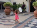 Little girl in Pink dress running happily with her Balloon.