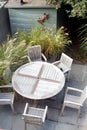 Wooden garden table and chairs in a small modern urban garden on patio with grasses and shed