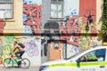 Ljubljana, Slovenia - August 16, 2018: A cyclist and a taxi cab pass in front of a graffited and colorful building in a sunny day