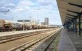 Ljubljana, Slovenia - August 15, 2018: A long freight train goes through the main railway station while some passengers wait for t