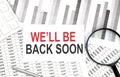 WE`LL BE BACK SOON text on paper with calculator,magnifier ,pen on the graph background Royalty Free Stock Photo