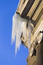 Large icicles hang from a house roof in winter. Dangerous large icicles. Death or injury danger.