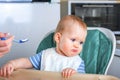 Llittle baby does not want to eat first complementary food. Disgruntled child at highchair