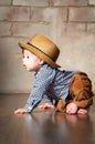 Llittle boy in retro hat and corduroy trousers learning to crawl on floor on all fours