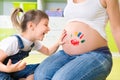 Llittle girl painting on pregnant belly Royalty Free Stock Photo