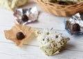 A llittle present, fresh flowers and some chocolate candies on a white wooden surface