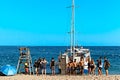 Lloret de mar, Spain - July 11, 2019: Yacht on the beach. Guys and girls on the background of the sea.