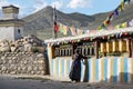 Old Nepalese woman commits a ritual prayer, touching the prayer drums on the street