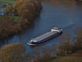 Loaded barge ship on Neckar River in autumn with discolored trees and bare vineyards on the banks. Royalty Free Stock Photo