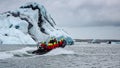 Photo of a boat approaching the blue enormous iceberg.