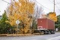 Loaded with container flat bed semi trailer without semi truck standing on the street parking with autumn trees on the side Royalty Free Stock Photo