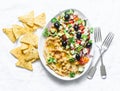 Loaded Greek salad hummus with corn tortilla chips on light background, top view. Delicious appetizer, tapas in a mediterranean Royalty Free Stock Photo