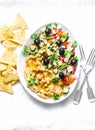 Loaded Greek salad hummus with corn tortilla chips on light background, top view. Delicious appetizer, tapas in a mediterranean Royalty Free Stock Photo