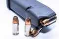 A loaded 9mm pistol magazine with three more hollow point bullets next to it Royalty Free Stock Photo