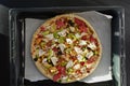 A loaded pizza on a pan with various toppings, a delicious fast food dish