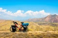 Loaded touring bicycle stands with moody dramatic panoramic mountains view and no cyclist