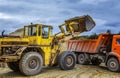 Loader excavator loads the ground in truck at the road construction Royalty Free Stock Photo