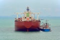 Loading anchored oil supertanker via a ship-to-ship oil transfer