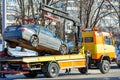 The work of a car tow truck on a city street on a winter sunny day