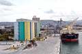 Loading cargo of cement clinker in bulk carrier by ships cranes in the port of Izmir, Turkey. Royalty Free Stock Photo