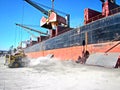 Loading cargo of cement clinker in bulk carrier by ships cranes in the port of Izmir, Turkey.