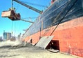 Loading cargo of cement clinker in bulk carrier by ships cranes in the port of Izmir, Turkey. Royalty Free Stock Photo