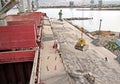 Loading cargo of cement clinker in bulk carrier by ships cranes in the port of Izmir, Turkey.