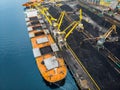 Loading coal anthracite mining in port on cargo tanker ship with crane bucket of train. Aerial top view Royalty Free Stock Photo