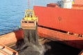 Loading coal from cargo barges onto a bulk carrier using ship cranes and grabs at the port of Samarinda, Indonesia. Royalty Free Stock Photo