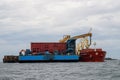 Loading coal from cargo barges onto a bulk vessel using ship cranes.