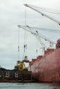 Loading coal from cargo barges onto a bulk vessel using ship cranes.