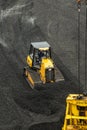 Loading coal from cargo barges onto a bulk vessel using ship cranes.