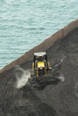 Loading coal from cargo barges onto a bulk vessel using ship cranes.