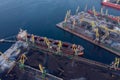 Loading coal mining in port on cargo tanker ship with crane bucket of train. Aerial top view Royalty Free Stock Photo