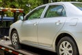 Loading a damaged broken car onto a tow truck while working for a towing company