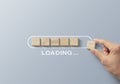 Loading, reboot, refresh or mindset concept. Hand putting wooden blocks in progress bar on gray background with the word LOADING Royalty Free Stock Photo