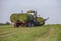 Loading and moving round bales of hay using auto loader trailer.