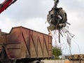 Loading scrap metal into a truck. Crane grabber loading metal rusty scrap in the dock Royalty Free Stock Photo