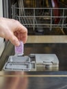 Loading the soluble-coated tablets in the dishwasher. Powder, dishwashing detergent and rinse aid. Washing dishes in the kitchen