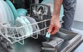 Loading the tablet into the dishwasher. A man puts the tablet in the dishwasher to wash dirty dishes Royalty Free Stock Photo