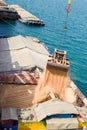 Loading wheat on cargo ship with crane and bucket. Shipment from a merchant ship to a small ship. Grapple crane fill wheat into