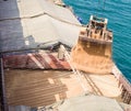 Loading wheat on cargo ship with crane and bucket. Shipment from a merchant ship to a small ship. Grapple crane fill wheat into