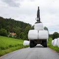 loading white grass rolls on country road in norway Royalty Free Stock Photo