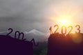 Silhouette sport man with 2022 and 2023 number new year on sunset sky at top of mountain abstract background. Happy new