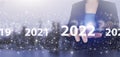 Loading year 2021 to 2022. Start concept. Hand touch digital screen hologram 2022 sign on city light blurred background. New year