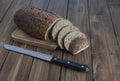 Loaf of black bread with a knife on a wooden board Royalty Free Stock Photo